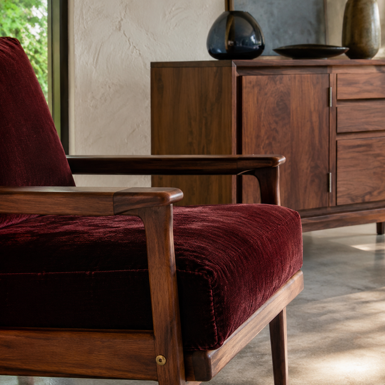 Close detail of oxblood chair, walnut and warm materials